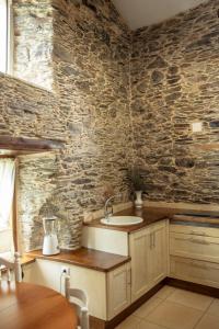 a kitchen with a sink and a stone wall at Lugar del Rio in Couzadoiro