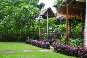 a garden with a bunch of flowers and a gazebo at sammy cottage senggigi in Mangsit