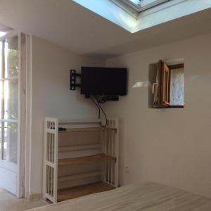 een slaapkamer met een flatscreen-tv aan de muur bij Les Hautes Roches in Collobrières