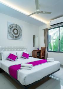 1 dormitorio con 1 cama grande con almohadas moradas en Nexstay Treats Inn, en Kozhikode