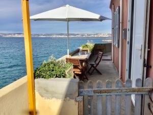 una mesa con sombrilla en el balcón de una casa en Cabanon Marseillais 45 m2 sur l'eau à Malmousque en Marsella