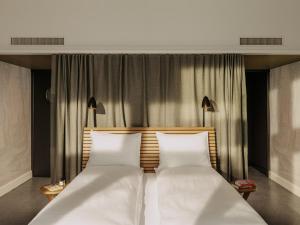 1 dormitorio con 2 camas blancas y 2 lámparas en Boutique & Design Hotel Volkshaus Basel en Basilea