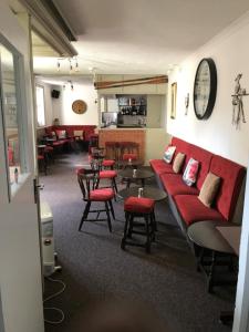 a waiting room with a red couch and tables and chairs at The Denewood in Sandown
