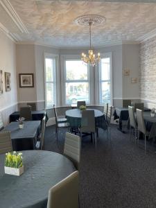 a dining room with tables and chairs and a chandelier at The Denewood in Sandown