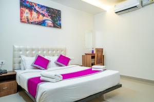 1 dormitorio con 1 cama grande con almohadas rosas en Nexstay Treats Inn, en Kozhikode