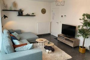 een woonkamer met een blauwe bank en een tv bij Vakantieverblijf 'Mara Cinco' met ruim terras in Oostende in Oostende