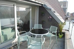 een patio met een tafel en stoelen op een balkon bij Vakantieverblijf 'Mara Cinco' met ruim terras in Oostende in Oostende