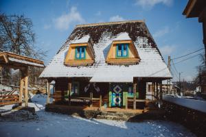 une cabane en rondins avec de la neige sur le toit dans l'établissement Casa Moroșenilor - Breb, à Breb
