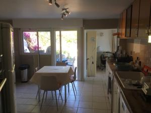 eine Küche mit einem Tisch und Stühlen sowie eine Küche mit einem Fenster in der Unterkunft Villa indépendante climatisée Tiuccia Bord de mer in Casaglione