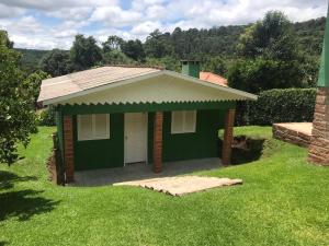 una pequeña casa verde con un garaje en el césped en Residenciais Casa Verde Gramado, en Gramado