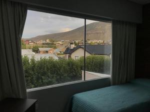 ventana de un dormitorio con vistas a la montaña en Del Sur Aparts en El Calafate