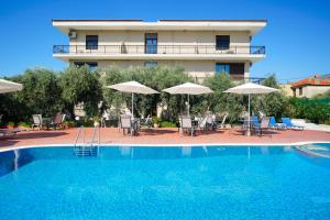 a hotel with a swimming pool with chairs and umbrellas at Meni Studios in Limenaria