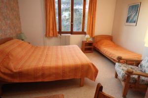 a bedroom with two beds and a chair and a window at Le Vieux Chalet in Embrun
