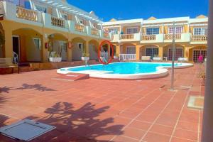 a courtyard with a swimming pool in front of a building at NEW Apartamento Caleta,Relax, Pool, Terrace, Wifi in Caleta De Fuste
