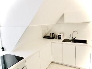 una cocina blanca con armarios blancos y fregadero en Apartamenty VIP, en Ustka