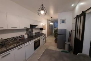 una cucina con mobili bianchi e un piano di lavoro nero di Idéal vieille Ville de Boulogne La Boulonnaise ! a Boulogne-sur-Mer