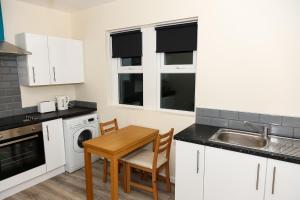 uma cozinha com armários brancos, uma mesa e um lavatório em AA Sunderland North em Sunderland