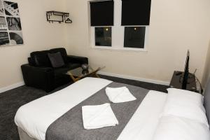 ein Schlafzimmer mit einem weißen Bett und einem schwarzen Stuhl in der Unterkunft AA Sunderland North in Sunderland