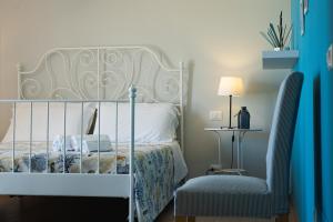 a bedroom with a white bed and a chair at Casa Azul in Castellammare del Golfo