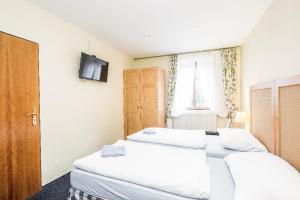 two beds in a room with a tv on the wall at Penzion u lípy in Jestřebí