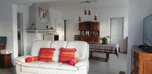 ein Wohnzimmer mit einer weißen Couch mit roten und gelben Kissen in der Unterkunft Grande maison de vacances in Lévignacq