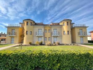 a large yellow building with a hedge in front of it at Residence Treporti - Carraro Immobiliare - Family Apartments in Cavallino-Treporti