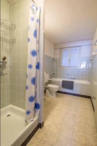 a bathroom with a tub and a toilet and a shower at Ferienwohnung Kurhaus in Adelboden