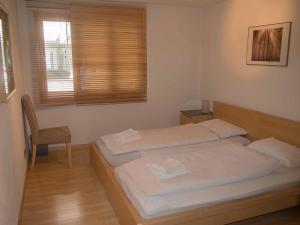 2 camas en una habitación con silla y ventana en Ferienwohnung Schützenrain, en Adelboden