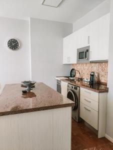 a kitchen with white cabinets and a marble counter top at Apartamentos Calma Rentals in Torremolinos