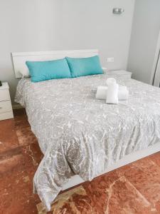a white bed with blue pillows on top of it at Apartamentos Calma Rentals in Torremolinos