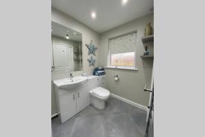 a bathroom with a toilet and a sink and a window at Modern and spacious open plan bungalow in Felixstowe