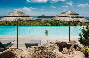 a resort with a pool with two umbrellas at Résidence Les Terrasses de Rondinara in Bonifacio