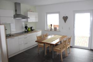 a kitchen with white cabinets and a wooden table and chairs at Ferienwohnung Seibel in Piesport