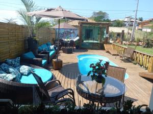 a patio with chairs and tables and an umbrella at Hostel Quintal do Rosa in Praia do Rosa