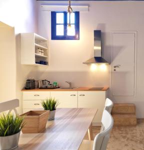 a kitchen with a wooden table and white cabinets at Psathi Blue Beta in Kimolos