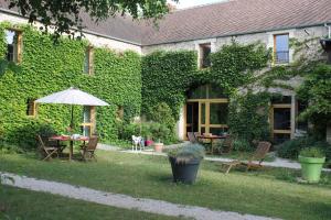 a garden with a table and chairs and an umbrella at La Côte Monsieur in Sanvigné