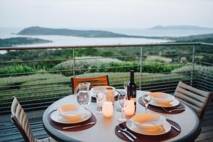 a table with plates and wine glasses on a balcony at Résidence Les Terrasses de Rondinara in Bonifacio