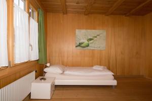 a small bedroom with a bed in a wooden wall at Im Zentrum in Adelboden