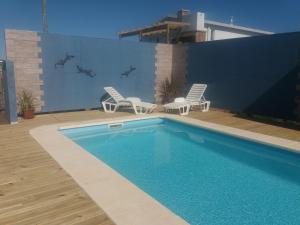 una piscina con 2 sillas de césped y una valla en Aroma de mar, en Sauce de Portezuelo
