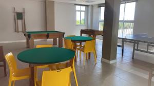 uma sala de jantar com mesas e cadeiras amarelas em Apartamento térreo 100 mts da praia VOG em Ilhéus