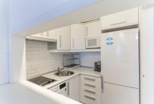 mała kuchnia z białymi szafkami i lodówką w obiekcie Apartamento Barquillo Duplex en Madrid w Madrycie +8 zdjęć