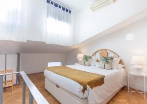 biała sypialnia z dużym białym łóżkiem i oknem w obiekcie Apartamento Barquillo Duplex en Madrid w Madrycie