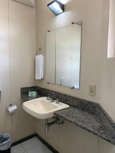a bathroom with a sink and a mirror at Cheverny Apart Hotel in Belo Horizonte