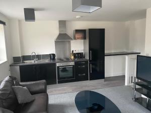 eine Küche mit schwarzen Schränken und einem Tisch im Wohnzimmer in der Unterkunft Doncaster Furnished House For Short Lets in Mexborough
