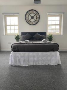 ein großes Bett in einem Zimmer mit einer Uhr an der Wand in der Unterkunft Doncaster Furnished House For Short Lets in Mexborough + 6 Fotos