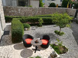 um pátio com 2 cadeiras e uma mesa num jardim em Apartments Corner em Dubrovnik