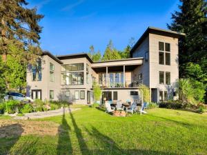 una casa grande con un patio con sillas delante en Liahona Guest House en Ucluelet