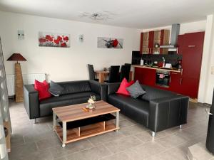 a living room with two black couches and a table at Ferienhaus am Schaalsee in Zarrentin