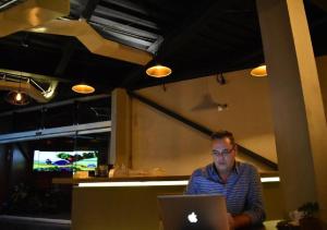 a man sitting at a table using a laptop computer at ESDUMA HK HOTEL Pachuca in Pachuca de Soto