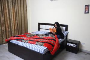 a woman sitting on a bed reading a book at The Desire Hostel in New Delhi